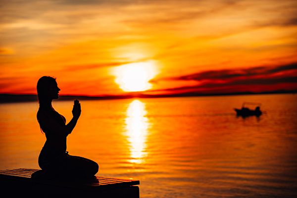 Silhouette einer Frau am See bei Sonnenuntergang